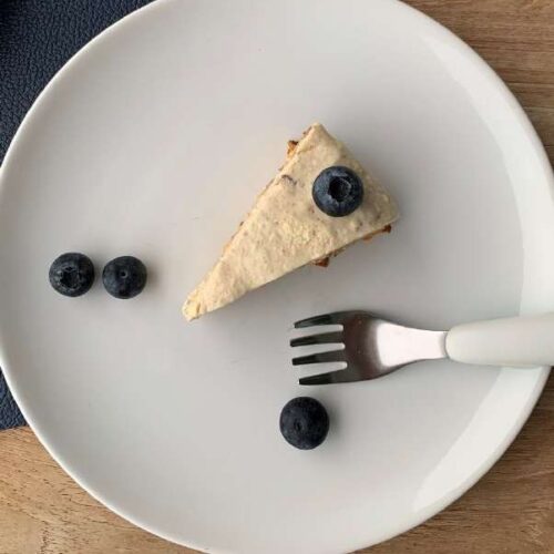 Stück Kuchen mit weißem Frosting ohne Zucker und Blaubeeren auf einem Teller
