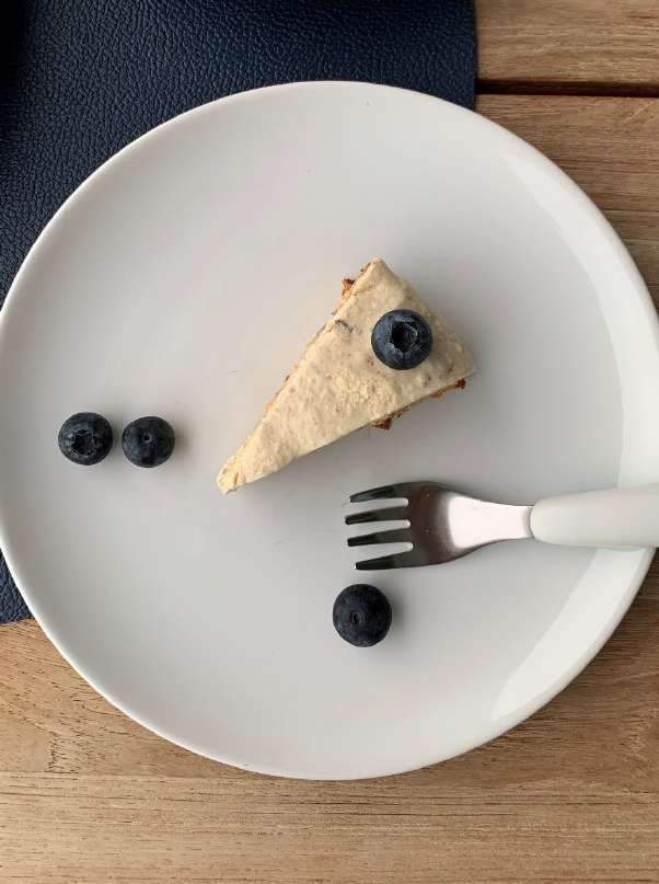 Stück Kuchen mit weißem Frosting ohne Zucker und Blaubeeren auf einem Teller